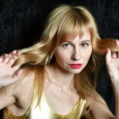 Kobieta z blond grzywką i niebieskimi oczami, zastanawiająca się, ile rośnie grzywka w tydzień.