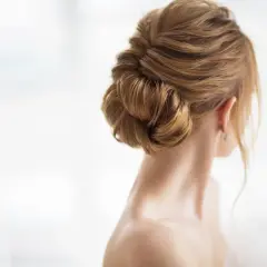 Elegancki, gładki kok z brązowych włosów, podkreślający linię szyi i ucha.