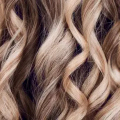 Falujące, jasne blond włosy z subtelnymi refleksami. To efekt flamboyage, techniki rozjaśniania nadającej naturalny wygląd.
